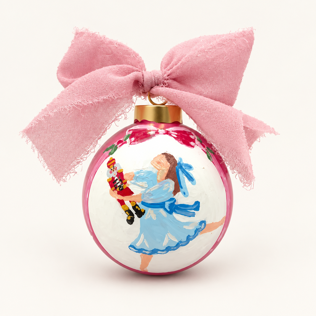Clara Nutcracker ornament with a pink bow on a warm-white background